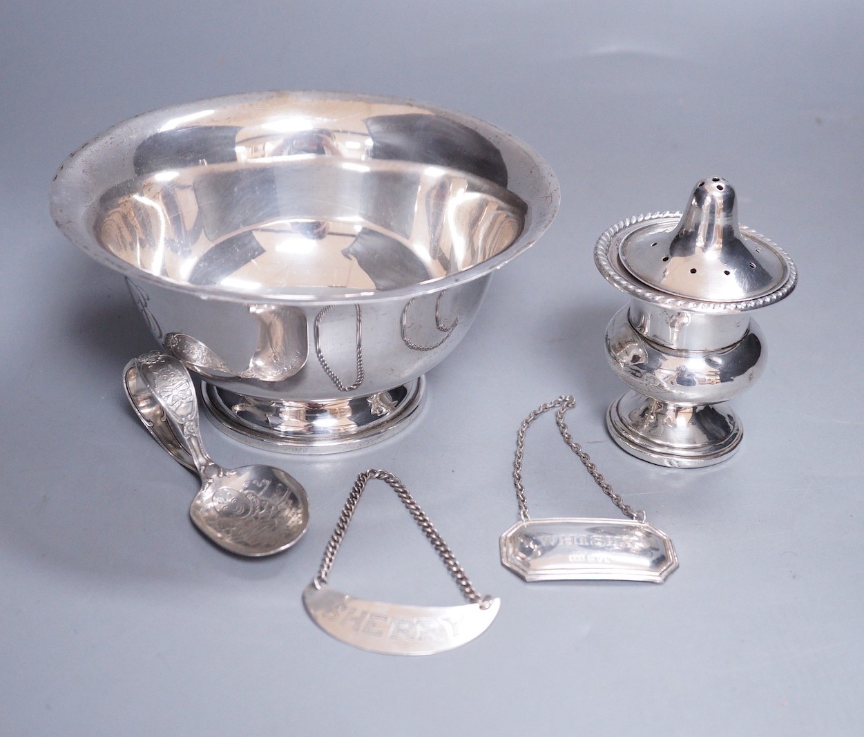 A group of small silver and white metal items including a sterling pedestal bowl. sterling 'Humpty Dumpty' child's spoon, a silver wine label, a sterling wine label, pierced silver lid and a sterling small vase